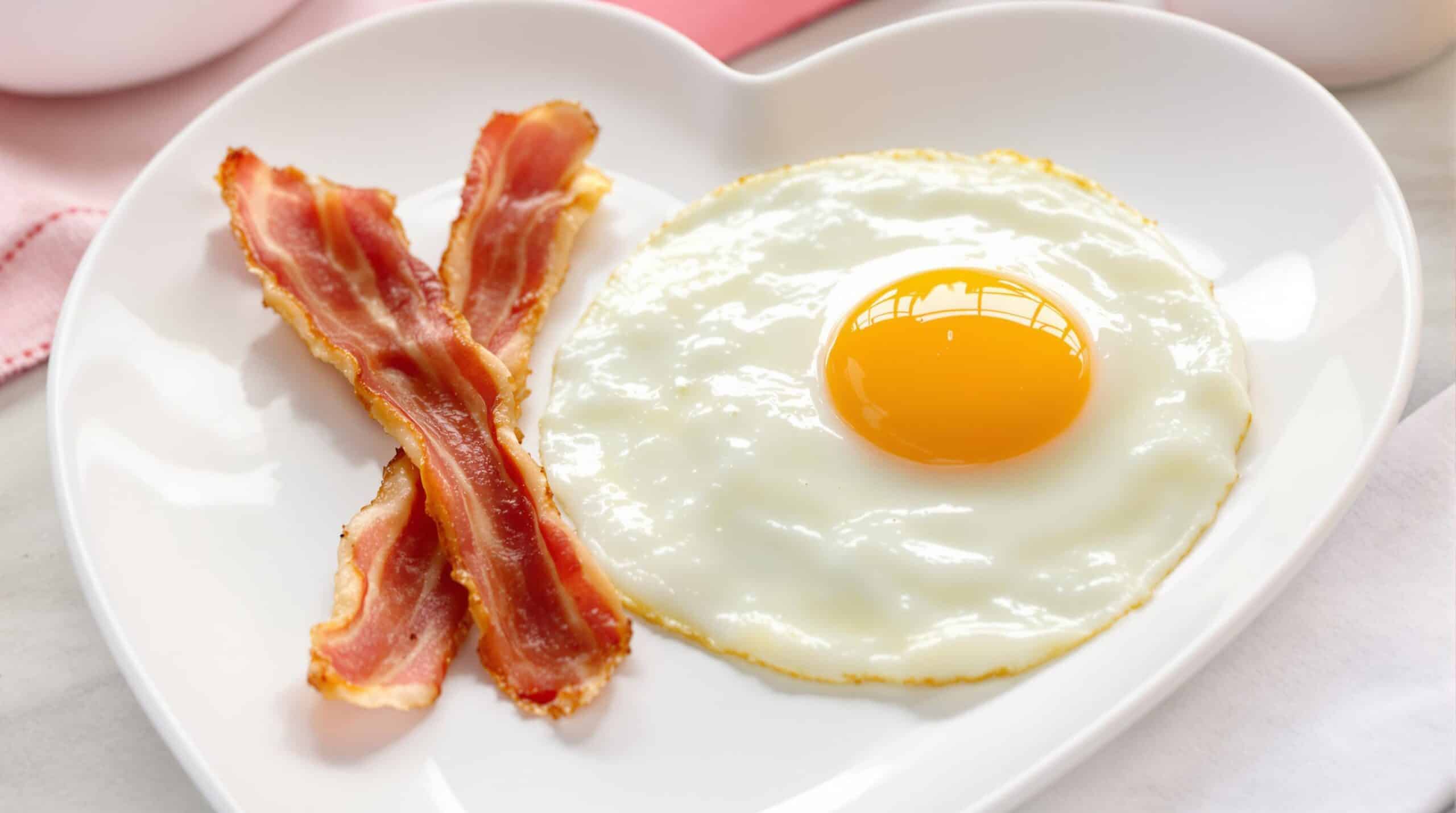 Uova e pancetta su un piatto a forma di cuore
