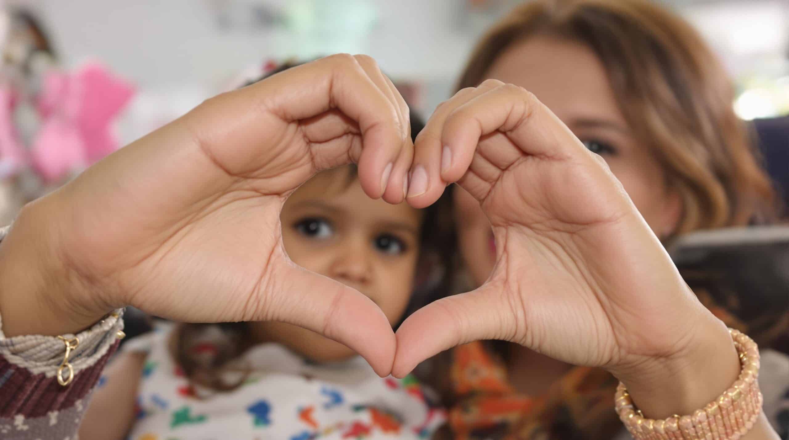 Una donna e sua figlia formano un cuore con le mani
