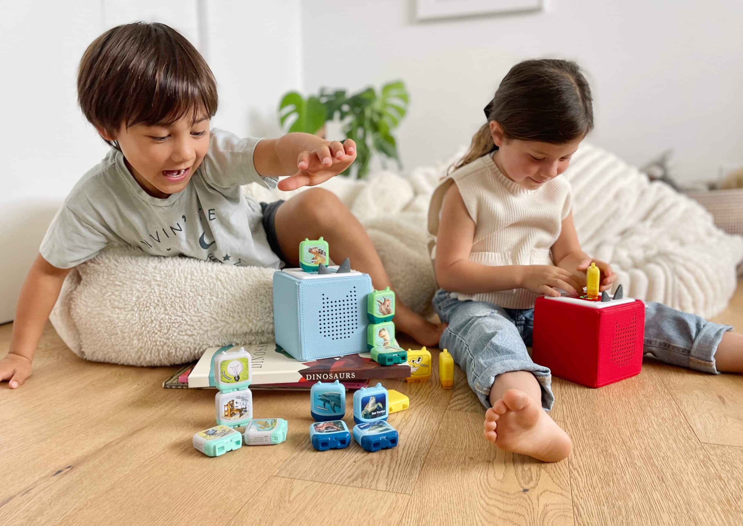 Due bambini sono seduti in una nursery e ascoltano i Tonies sui loro Toniebox.